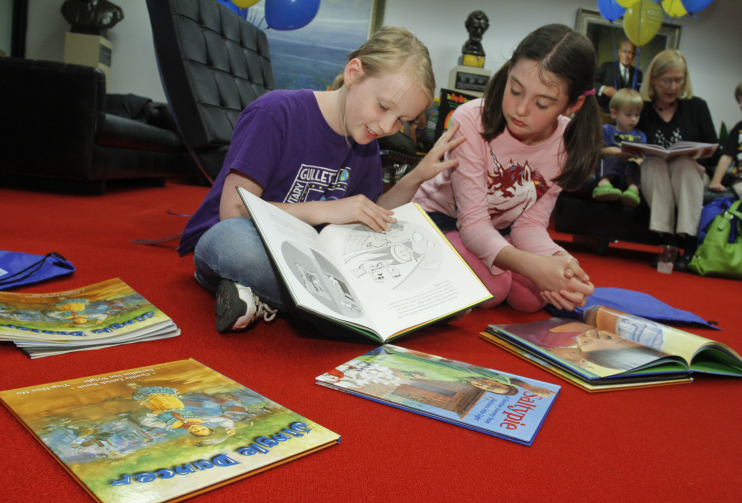 2 girls reading books on the floor