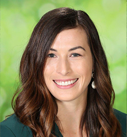 Erin Bailey smiles in front of a green background. She is the Director of Programs and Content at Reading Is Fundamental.